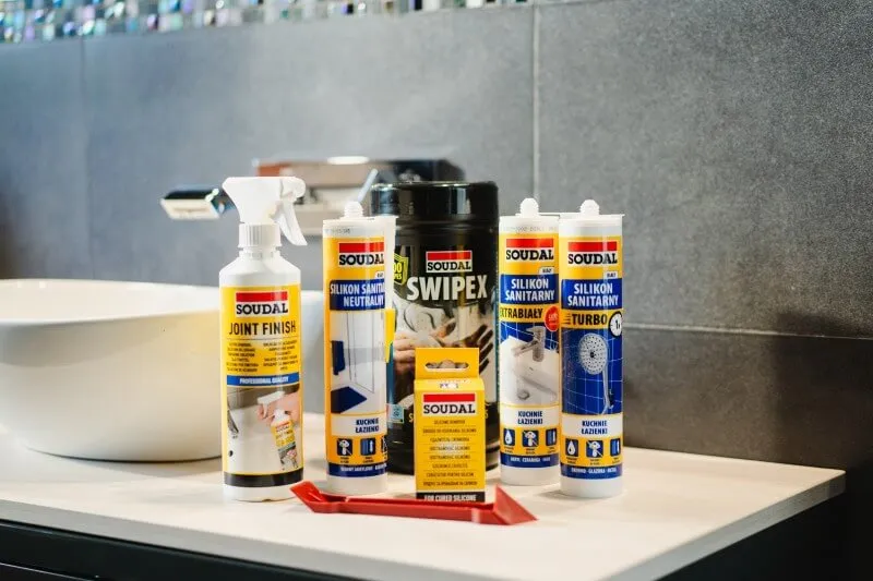 Produkty marki Soudal przydatne w uszczelnianiu łazienki stoją obok siebie na blacie szafki łazienkowej