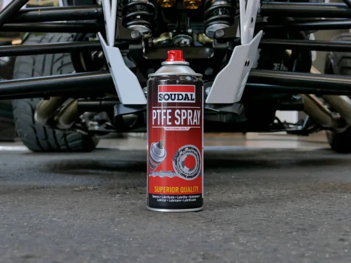 PTFE Spray marki Soudal stoi na warsztatowej podłodze przed pojazdem