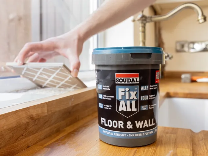Klej Soudal Fix All Floor & Wall w wiadrze podczas montażu płytek — uniwersalny klej hybrydowy do podłóg i ścian stosowany w pracach wykończeniowych.