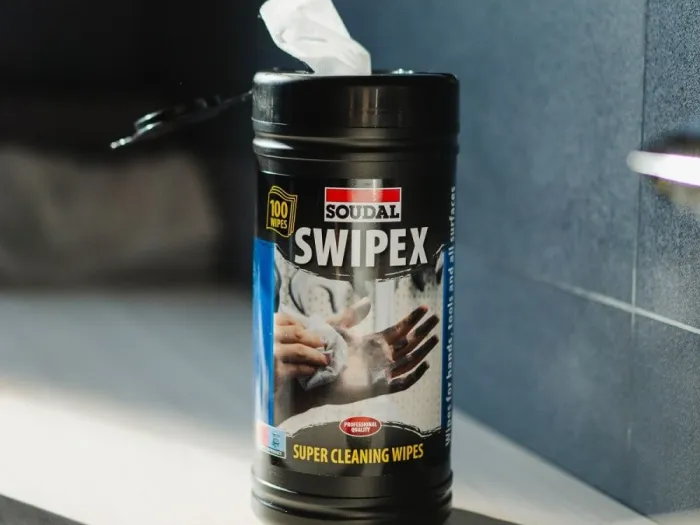Chusteczki czyszczące Swipex marki Soudal stoją na blacie w łazience obok ledwo widocznej umywalki