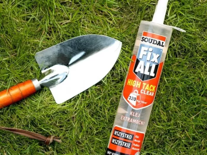 Fix All High Tack leży na trawie obok metalowej łopatki
