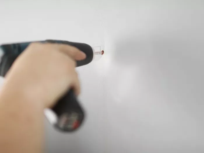 Ręka mężczyzny wywierca dziury w ścianie wiertarką